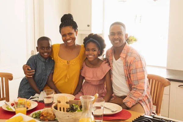 快適な自宅のダイニング ルームでカメラを見て幸せなアフリカ系アメリカ人の家族の正面図 — ストック写真