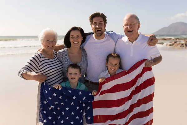 太陽の下 ビーチでアメリカの国旗に立って幸せな多世代家族のフロント ビュー — ストック写真