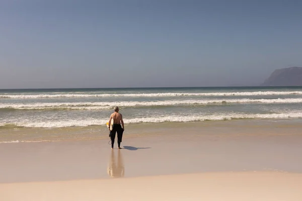 Arka Planda Dağlar Ile Sahilde Surfboard Ile Ayakta Kıdemli Erkek — Stok fotoğraf