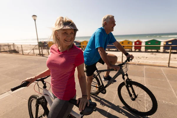 在海滩上的长廊上骑自行车的活跃的高级夫妇的侧视图 — 图库照片