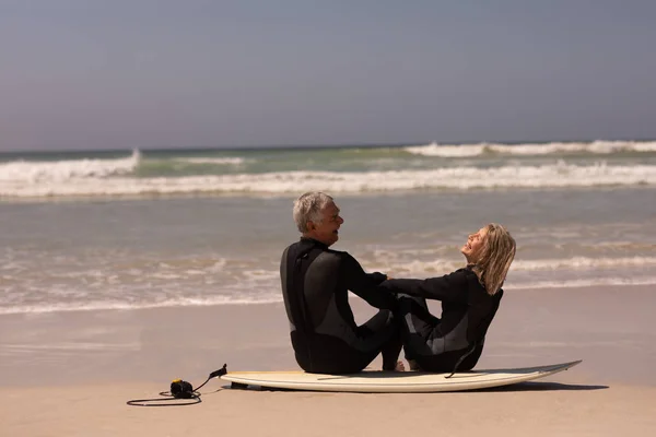 Widok Boczny Szczęśliwa Para Senior Siedzący Deskę Surfingową Plaży Promieniach — Zdjęcie stockowe