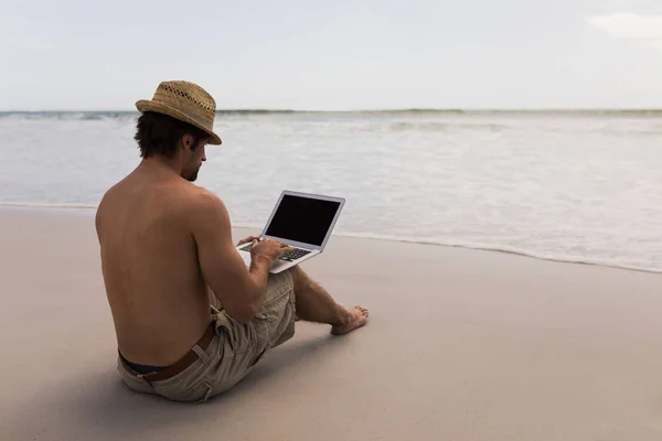 Widok Tyłu Shirtless Młody Człowiek Kapelusz Pomocą Laptopa Plaży — Zdjęcie stockowe