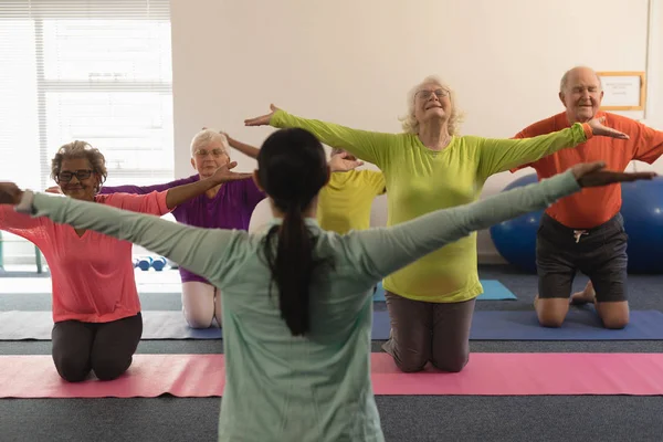 Entrenadora Joven Que Ayuda Personas Mayores Con Brazos Tensados Gimnasio — Foto de Stock