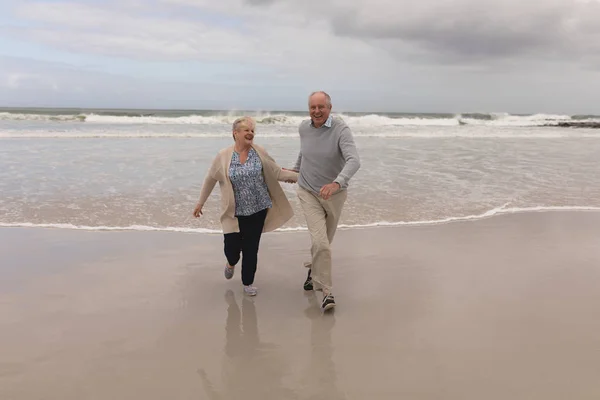 活跃的高级夫妇在海滩上手拉手的前景 — 图库照片