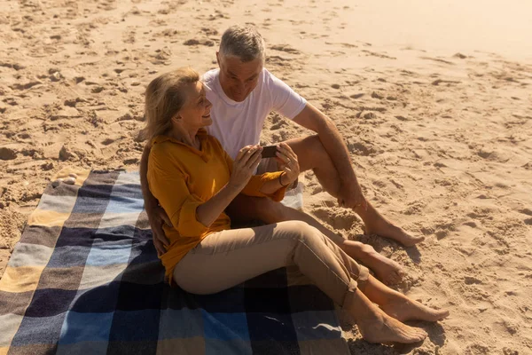 通过海滩手机上的照片查看活跃的高级夫妇的侧视图 — 图库照片