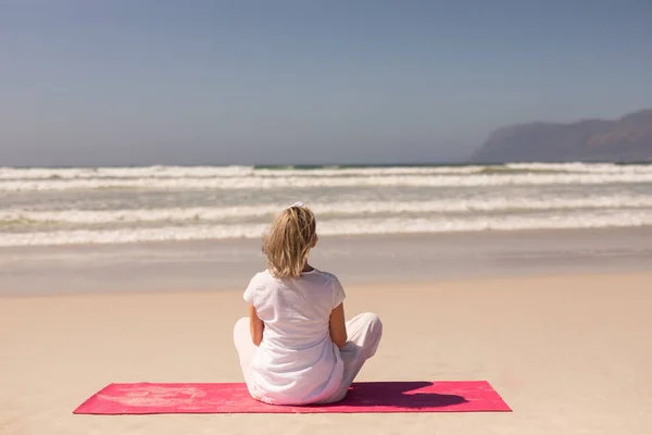 Vista Trasera Mujer Mayor Meditando Playa Día Soleado Con Montañas —  Fotos de Stock