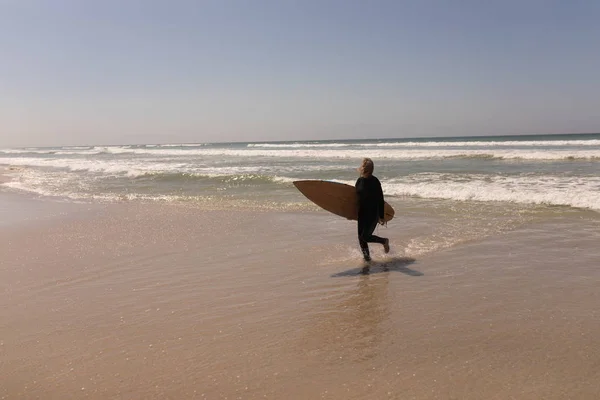 Widok Boku Aktywny Senior Surfera Kobiece Chodzenie Deski Surfingowej Plaży — Zdjęcie stockowe