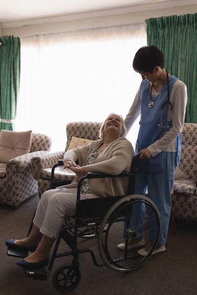 女医生在家中客厅与坐在轮椅上的残疾老年妇女互动的正面看法 — 图库照片