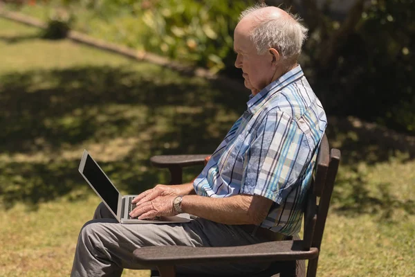 Vista Lateral Homem Idoso Ativo Usando Laptop Enquanto Sentado Banco — Fotografia de Stock