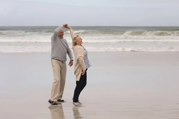 活跃的高级夫妇在海滩上一起跳舞的侧视图 — 图库照片