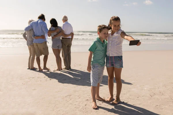 携帯電話で Selfie を取って兄弟ながらビーチを背景に 家族の地位 — ストック写真