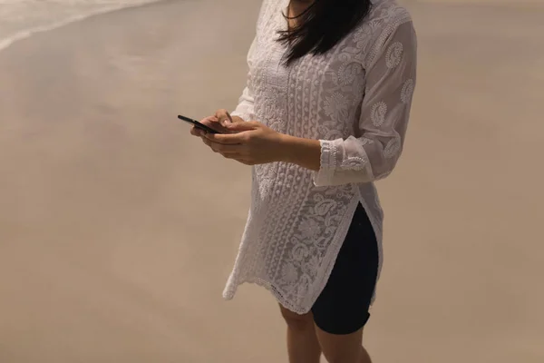 在阳光下使用手机在海滩上的年轻女子的中段 — 图库照片