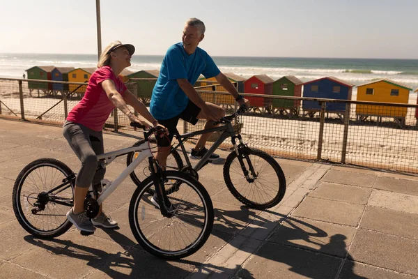 在海滩上的长廊上骑自行车的活跃的高级夫妇的侧视图 — 图库照片