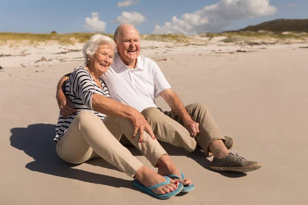 在阳光下坐在沙滩上的幸福的老夫妇的正面景色 — 图库照片