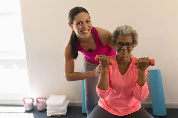 在健身工作室里帮助老年女性的快乐女教练的正面看法 — 图库照片
