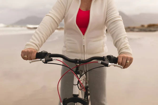 Seção Intermediária Mulher Sênior Andando Bicicleta Praia Contra Montanhas Fundo — Fotografia de Stock