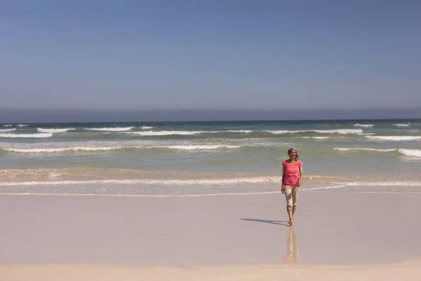太陽の下 ビーチの上を歩く年配の女性の正面図 — ストック写真