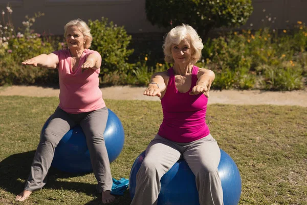 Front view of senior women exercising on a exercise ball in the park - Stoc...