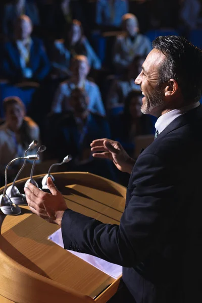 Side view of businessman standing and giving presentation in the auditorium