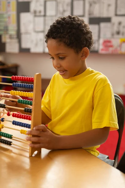 小学校の教室でそろばんを使った数学学習かわいい混血少年の正面図 — ストック写真