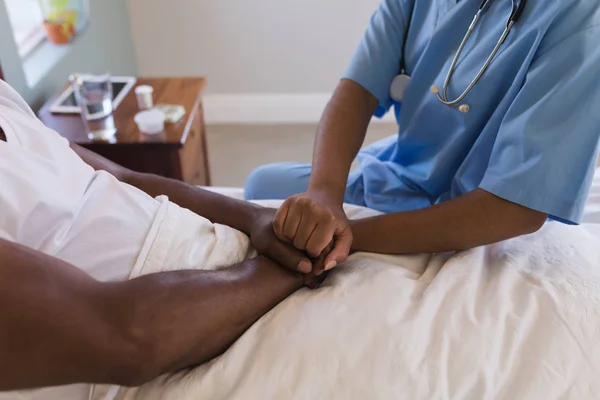 アフリカ系アメリカ人の女性医師が自宅の寝室でシニアのアフリカ系アメリカ人を慰めるの半ばセクション — ストック写真
