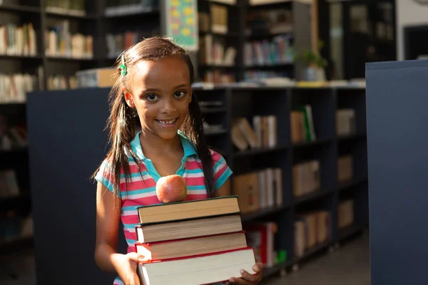 Vista Frontal Feliz Colegial Mestiça Segurando Pilha Livros Maçã Biblioteca — Fotografia de Stock