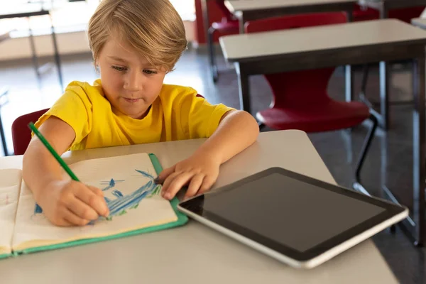 초등학교 교실에서 책상에 노트북에 스케치를 그리는 소년의 — 스톡 사진