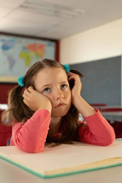 在小学的教室里 有思想的悲伤的高加索女孩靠在桌子上的前面 — 图库照片