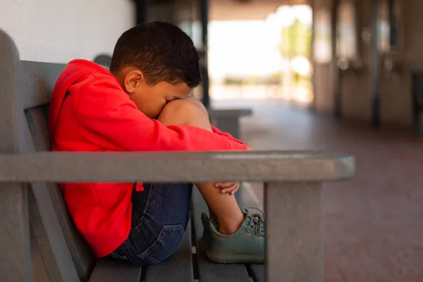 Zijaanzicht Van Triest Gemengd Ras Schooljongen Alleen Zittend Bank Gang — Stockfoto