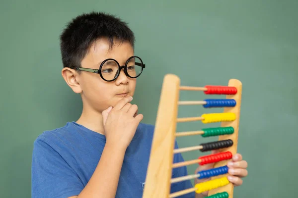 Front View Thoughtful Asian Boy Learning Math Abacus Green Chalkboard — Stock Photo, Image