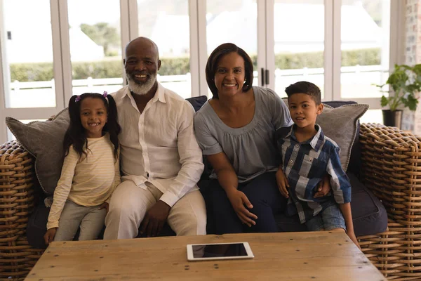 Front view of a multi-generation African American family sitting on sofa in living room at home