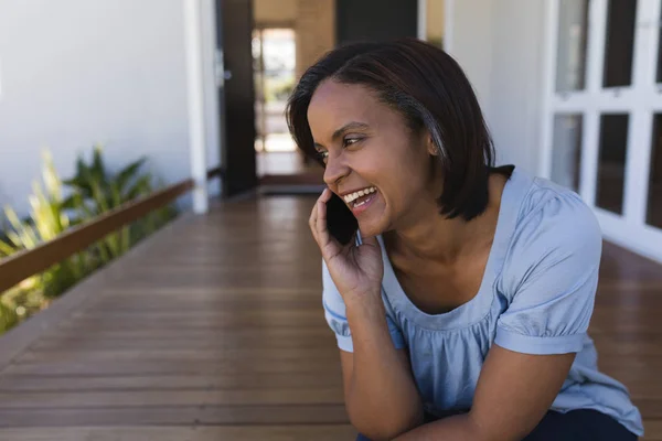 自宅のベランダで携帯電話で話している成熟した女性の正面図 — ストック写真