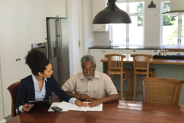 シニアのアフリカ系アメリカ人と自宅に書類を議論する若いアフリカ系アメリカ人の不動産業者の正面図 — ストック写真