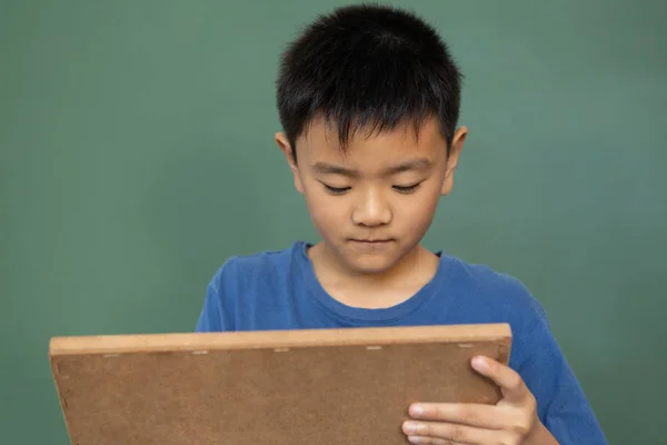 Vooraanzicht Van Aziatische Schooljongen Schrijven Krijt Leisteen Tegen Groene Schoolbord — Stockfoto