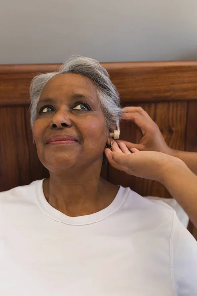 一名非洲裔美国女医生在家里耐心地为非洲裔美国高级妇女配备助听器 — 图库照片
