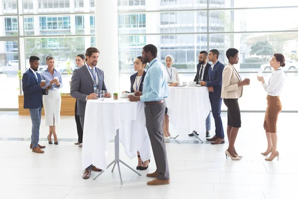 Front of view of diverse business people interacting with each other at table in office lobby