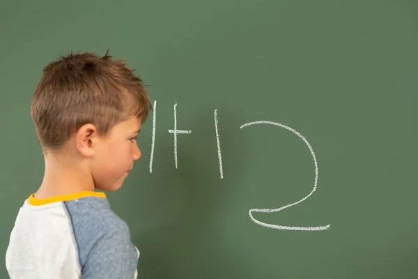 Vista Lateral Lindo Colegial Caucásico Haciendo Matemáticas Pizarra Verde Aula — Foto de Stock