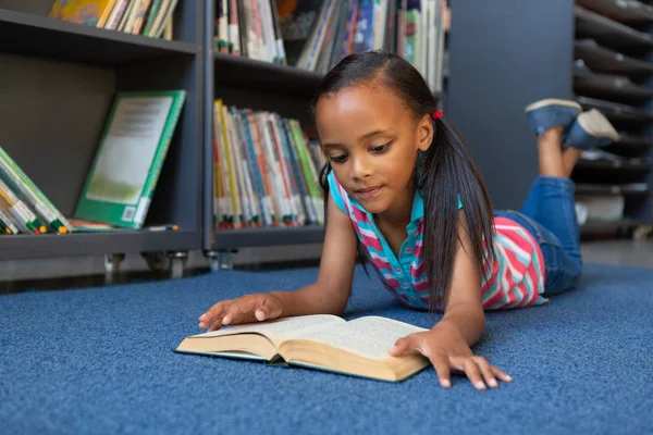 一个可爱的混血女学生躺在学校图书馆里看书的正面 — 图库照片
