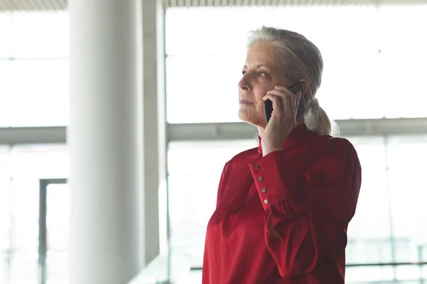 现代办公楼中的高级高加索女商人在手机上交谈的侧视图 — 图库照片
