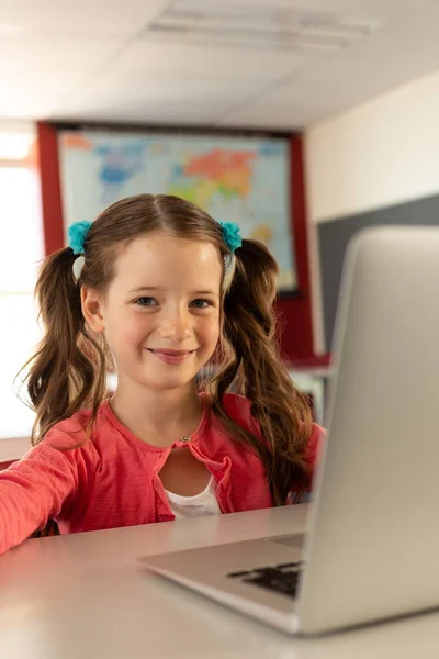 Widok Przodu Uśmiechnięta Dziewczynka Kaukaski Laptopa Siedząc Przy Biurku Klasie — Zdjęcie stockowe