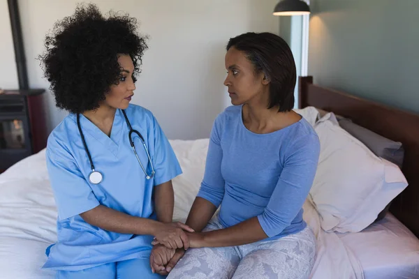 年轻的非裔美国女医生在家里的卧室里安慰非洲裔美国高级妇女的正面看法 — 图库照片