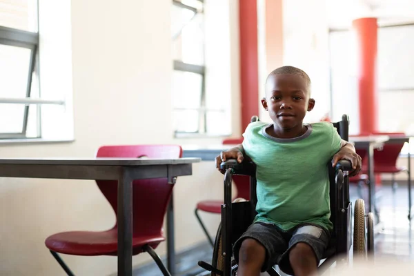 小学校の教室で車椅子に座ってカメラ目線の男子生徒にアフリカ系アメリカ人の正面の無効になっています — ストック写真