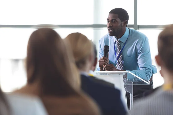 近代的なオフィスビルのビジネス セミナーで話すアフリカ系アメリカ人実業家スピーカーの側面図 — ストック写真