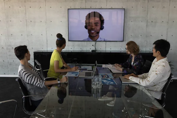 High view of sitting mixed race business colleagues attending a video call in a conference room at modern office