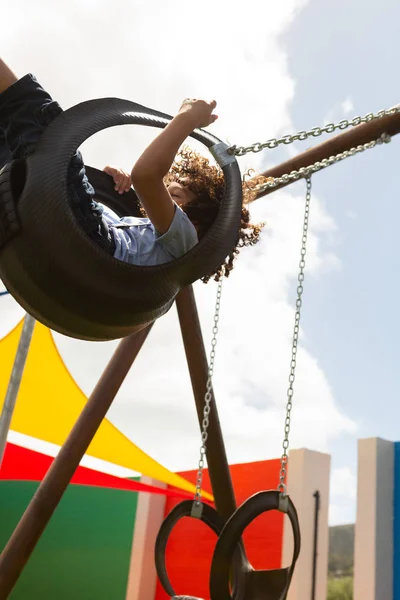 晴れた日に校庭でスイングで遊んで混血少年の側面図 — ストック写真