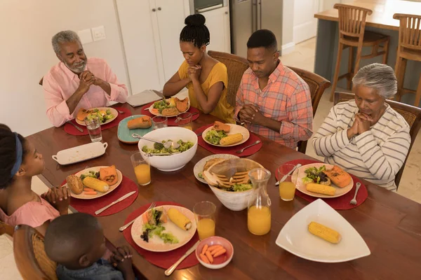 自宅のダイニング テーブルで食事する前に一緒に祈ってアフリカ系アメリカ人の多世代家族のハイアングル — ストック写真