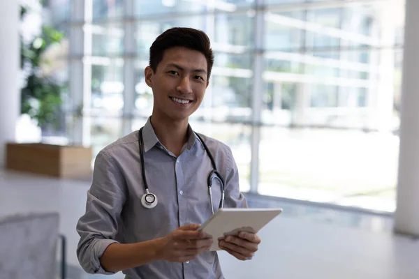 在医院使用数字平板电脑的快乐年轻亚洲男医生的肖像 他对着镜头微笑 — 图库照片