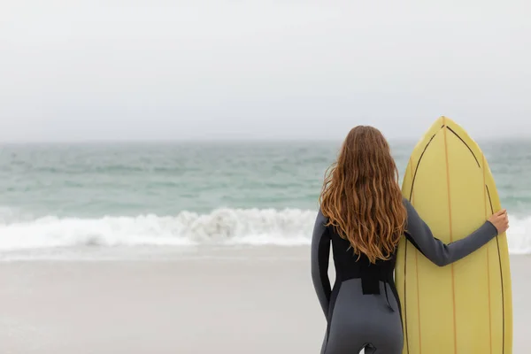 Widok Tyłu Kobiece Surfera Stojąc Deski Surfingowej Plaży — Zdjęcie stockowe