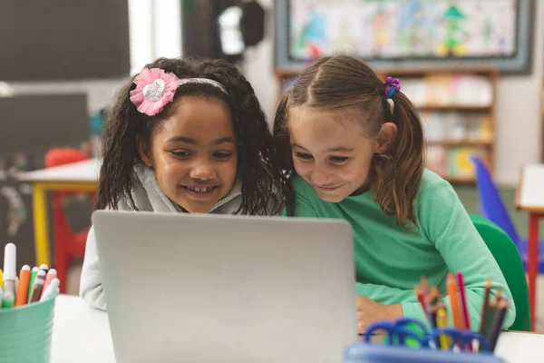 彼らは学校で教室で自分のコンピュータに取り組んでいる間 笑顔2人の女子学生の表面レベルのビュー — ストック写真