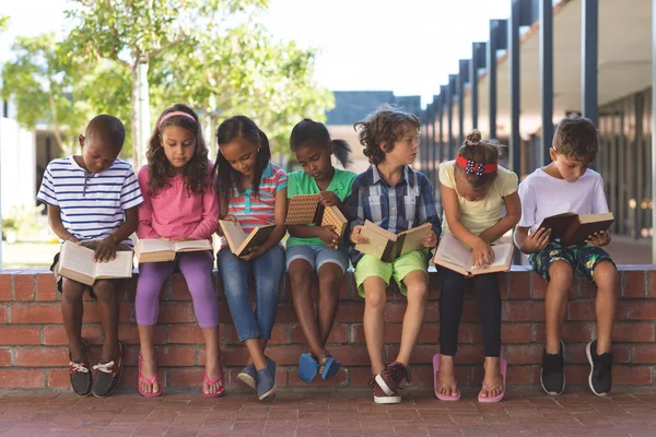 Vista Frontal Estudantes Multi Étnicos Lendo Livros Enquanto Sentados Parede — Fotografia de Stock